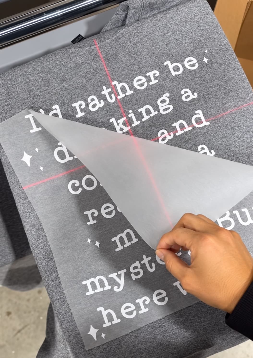 Peeling the film off a freshly pressed transfer on a heather gray hoodie